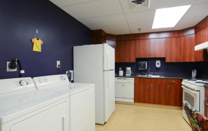 A combined laundry and kitchen area with appliances including a washing machine, dryer, refrigerator, and dishwasher.