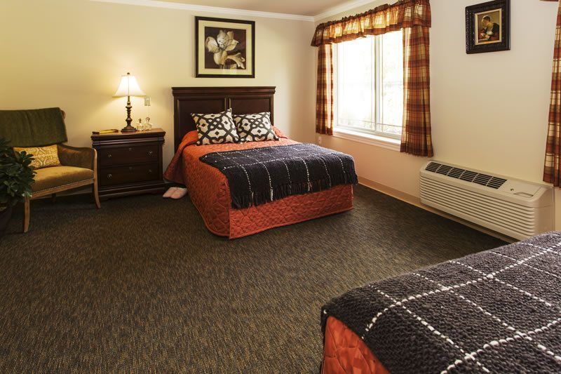 A cozy hotel room with two beds, stylish decor, and natural lighting.