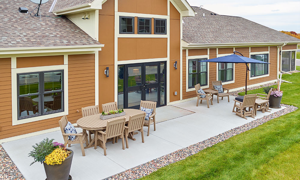 A spacious outdoor patio with tables, chairs, and an umbrella, adjacent to a building.