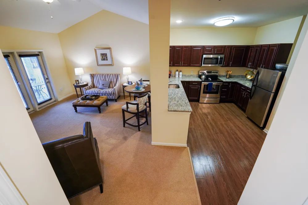 An open floor plan combining a cozy living room and a modern kitchen with wood flooring and carpet.