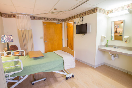 A well-lit hospital patient room equipped with a bed, television, and sink.