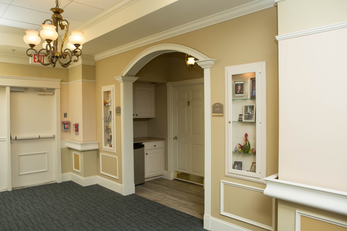 A well-lit hallway with elegant decor, featuring an archway and chandelier.