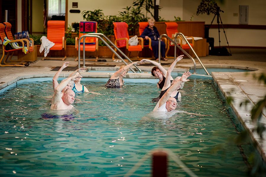 A group of people participating in a water aerobics class at an indoor swimming pool.