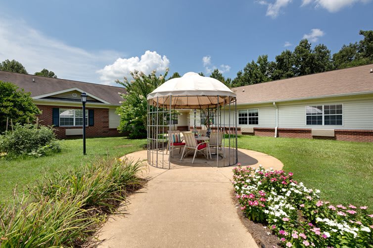 A well-maintained garden with a gazebo and outdoor seating area on a sunny day.