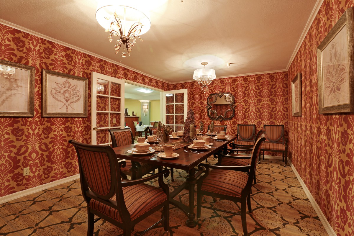 A classic dining room with ornate wallpaper and a formal table setting.