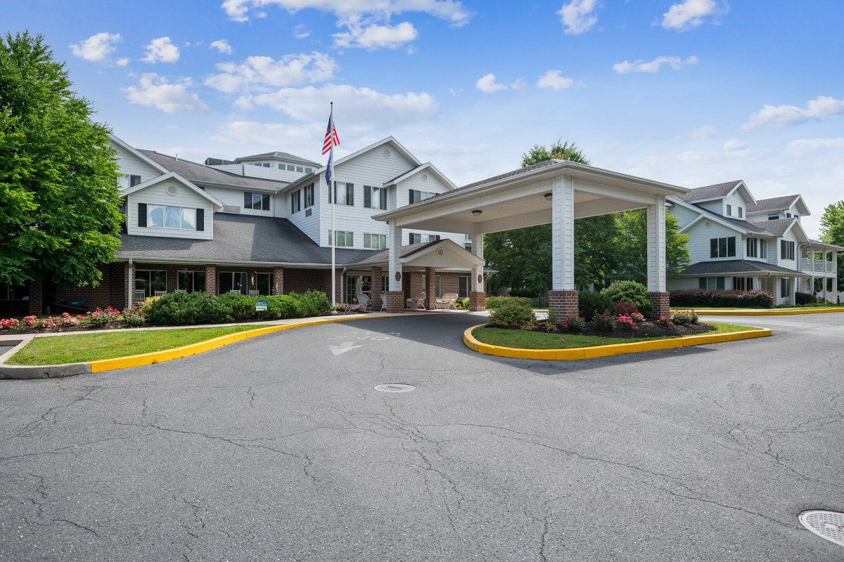 A well-maintained entrance of a residential building with landscaping and an American flag.