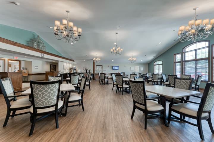 A spacious and elegant dining area with chandeliers, featuring modern furniture and wooden flooring.