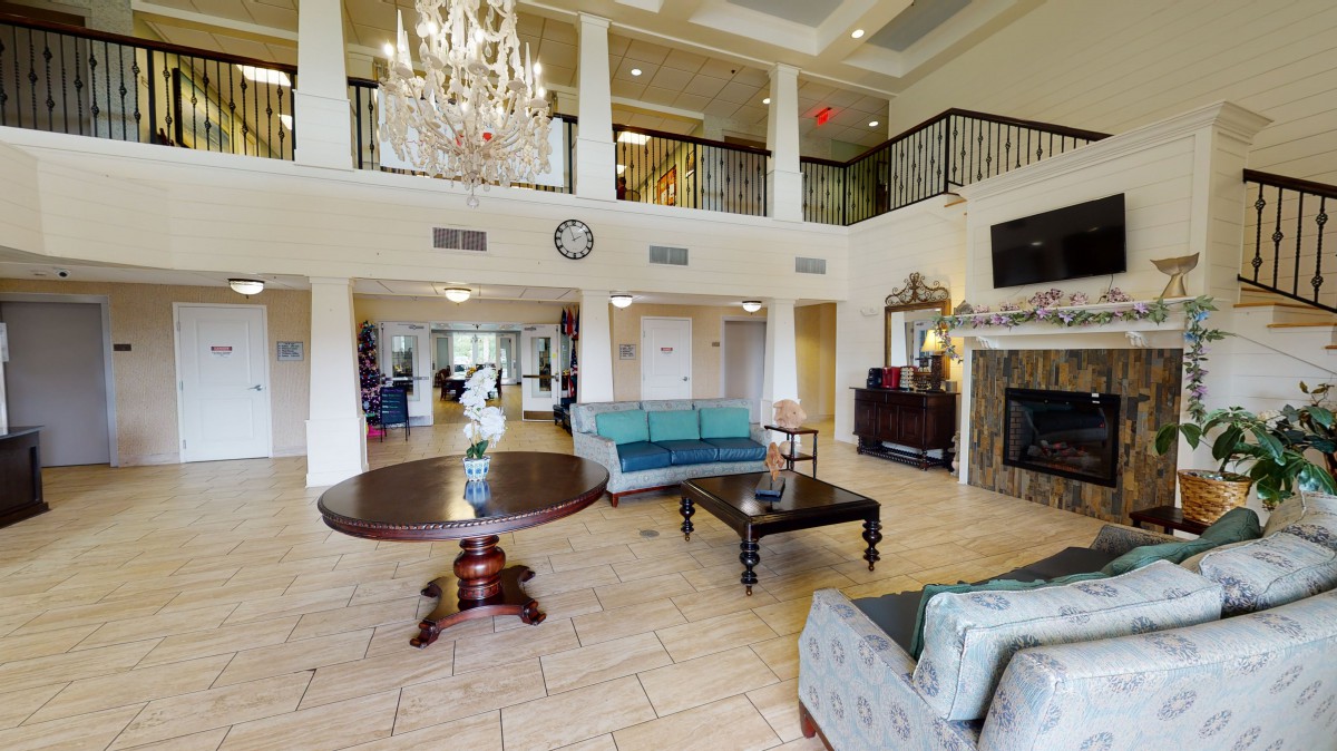 A spacious and elegant lobby featuring a chandelier, comfortable seating, and a grand staircase.