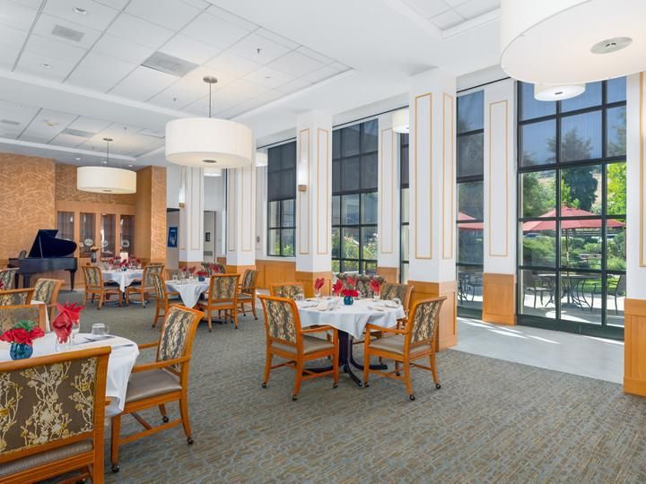 A spacious and elegantly designed restaurant dining area with large windows and neatly arranged tables and chairs.