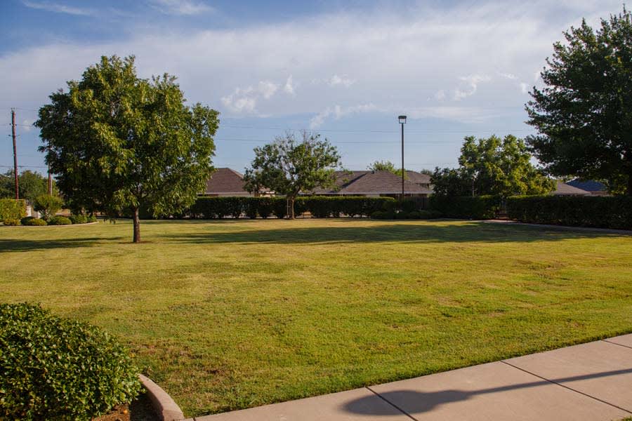 A peaceful park with green grass and trees in a residential area.