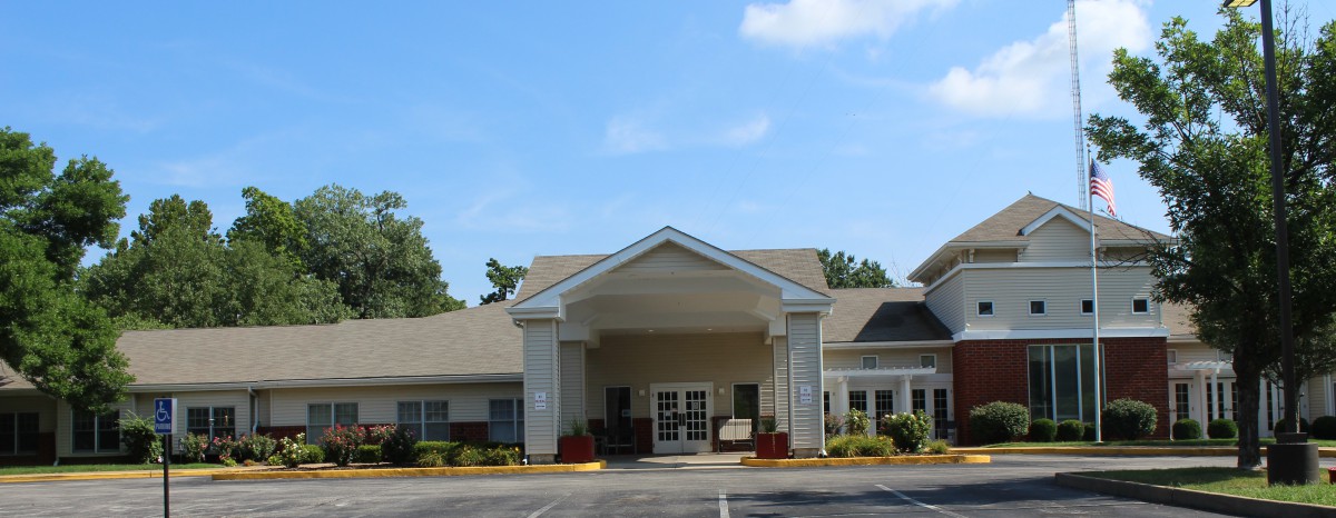A view of a residential building entrance with a gabled roof and landscaped surroundings.