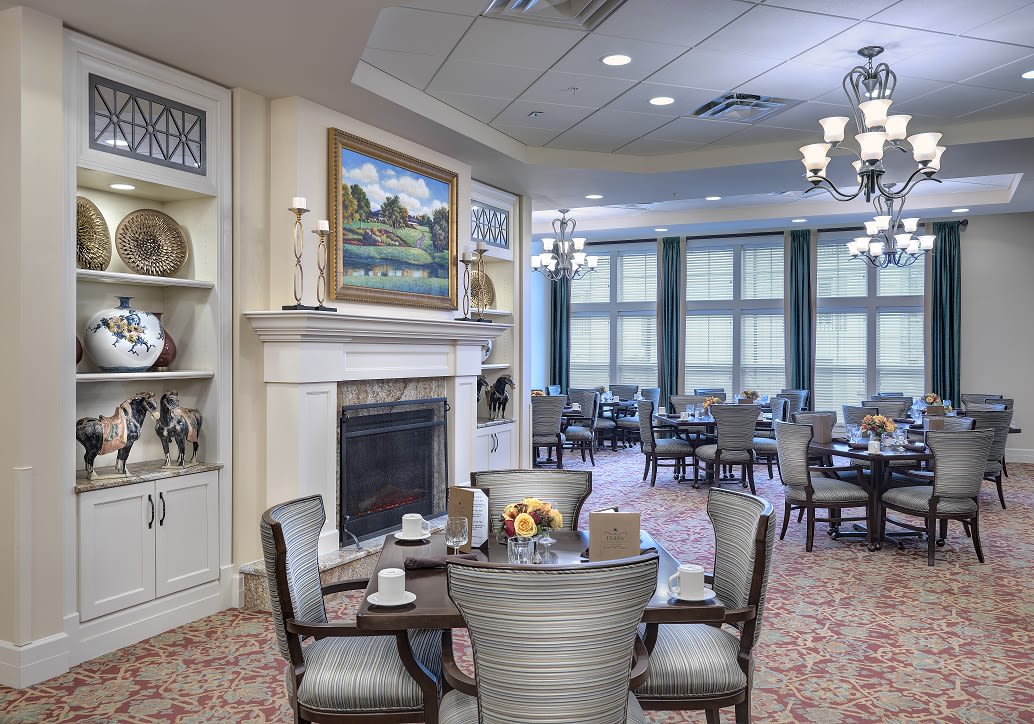 A cozy dining room with elegant furnishings, featuring a fireplace and large windows.