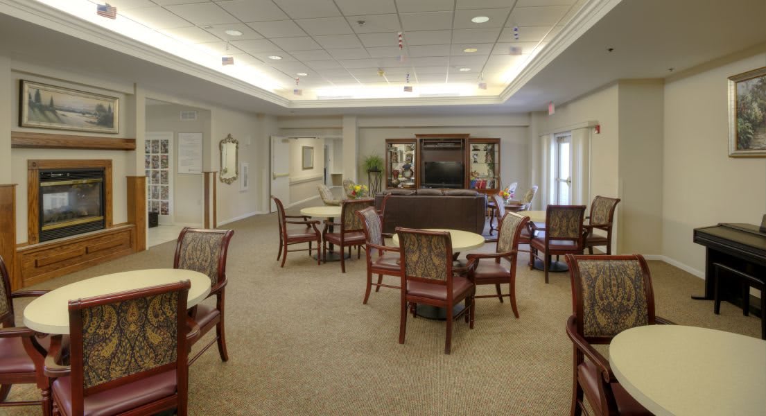 A spacious and well-lit seating area with tables and chairs, suitable for gatherings or meetings.