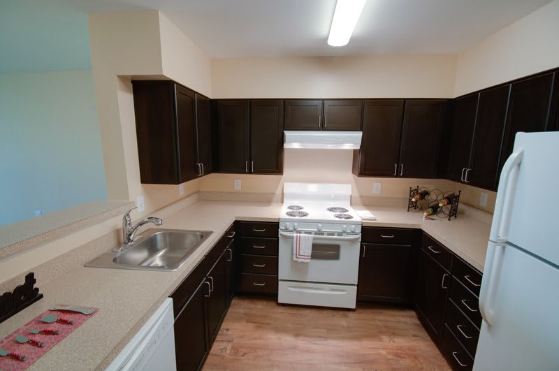 A modern kitchen with dark cabinets and a white stove.