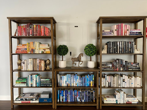 A cozy and organized bookshelf displaying a variety of colorful books and decorative plants.