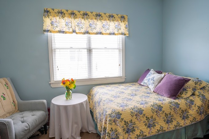 A cozy bedroom with floral decor and natural lighting.