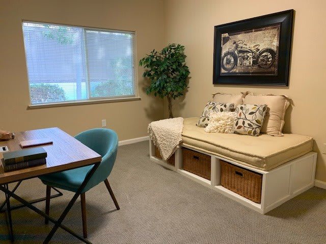 A cozy home office with a desk, chair, and a daybed featuring storage baskets underneath.