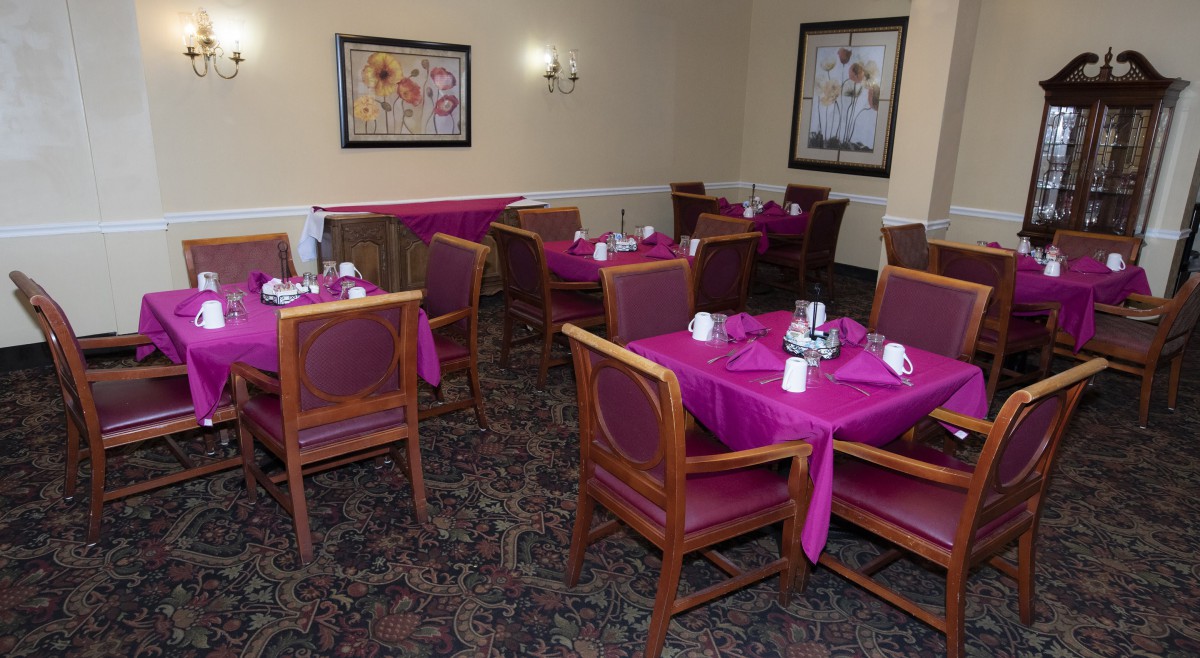An elegant dining area with neatly arranged tables and chairs, decorated with purple tablecloths.
