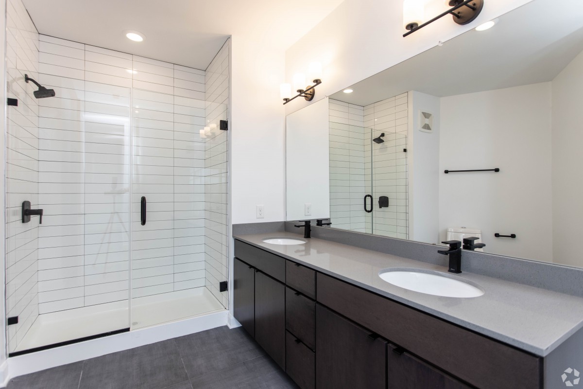 A modern bathroom featuring a spacious shower, double sink vanity, and sleek black fixtures.