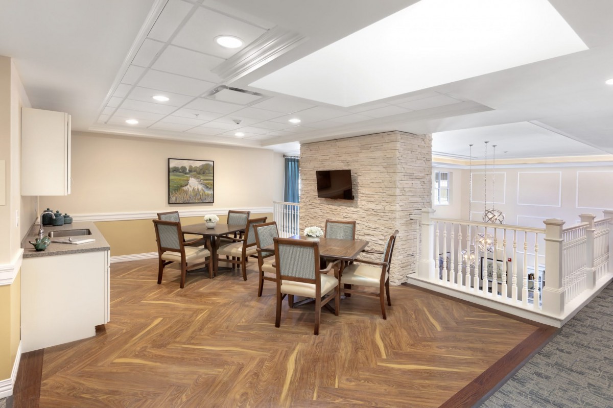 A modern dining area with tables, chairs, and a mounted television on a wooden floor.