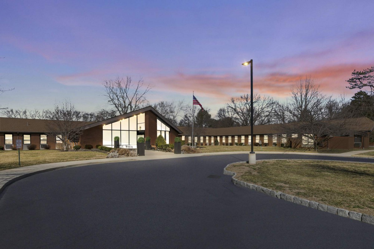 A building complex at sunset with a flagpole and surrounding trees.