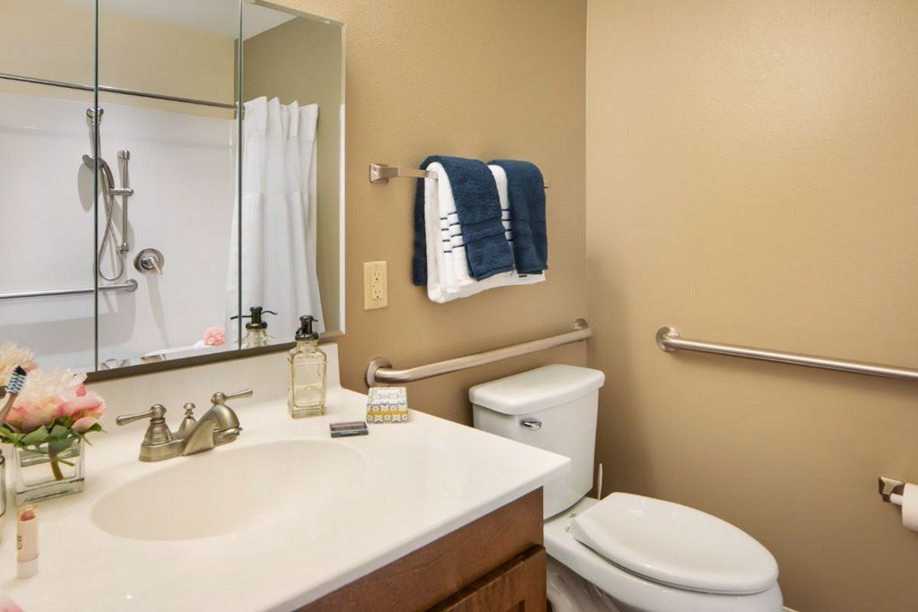 A neatly arranged bathroom with a toilet, sink, and towels on display.