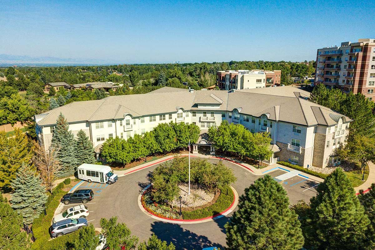 Aerial view of a suburban building surrounded by trees and a parking lot.