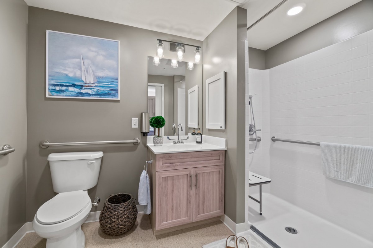 Modern bathroom interior with a sink, toilet, and shower, complemented by wall art and stylish lighting.