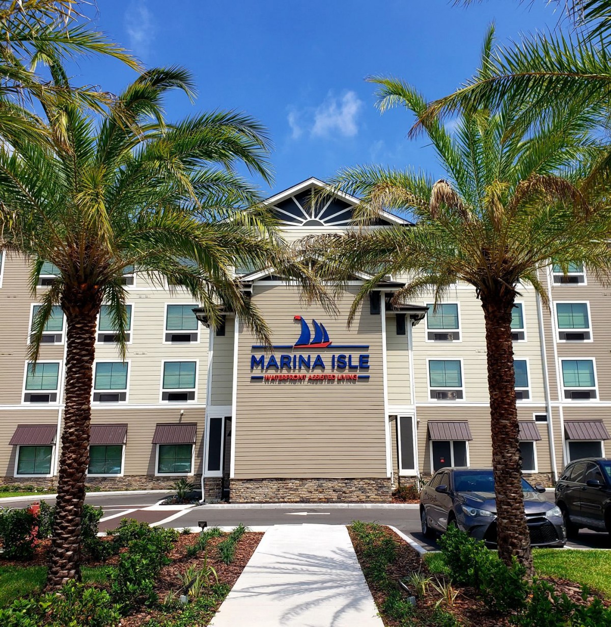 A modern hotel building with palm trees against a clear blue sky.