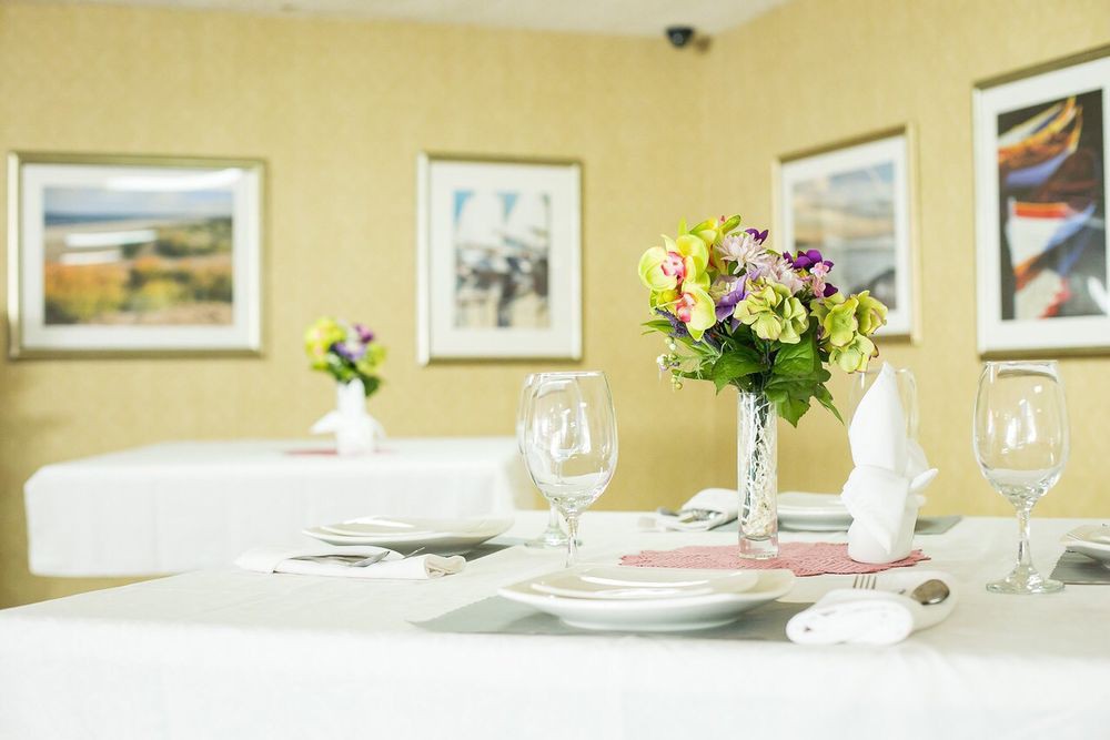 An elegantly set dining table with floral centerpieces and white dinnerware.