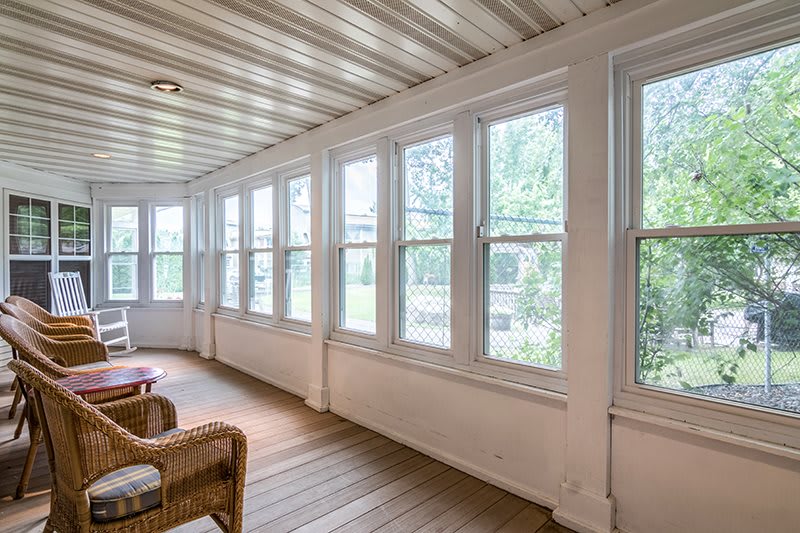 A bright sunroom with large windows and wicker furniture.