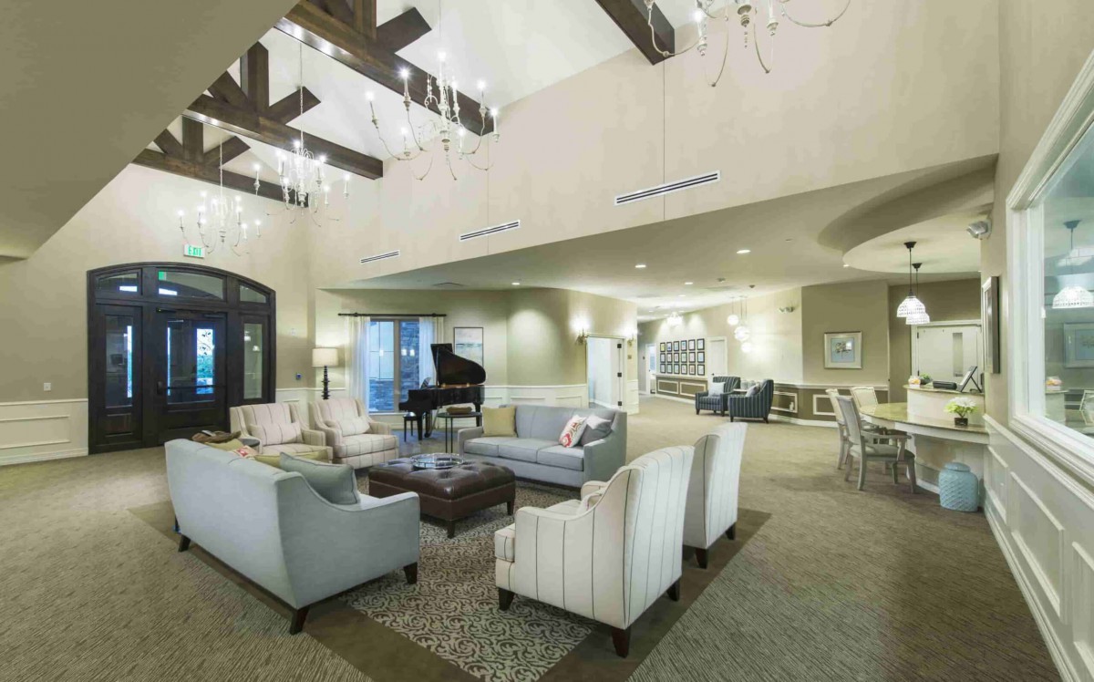 A spacious and modern living room with elegant chandeliers and comfortable seating.