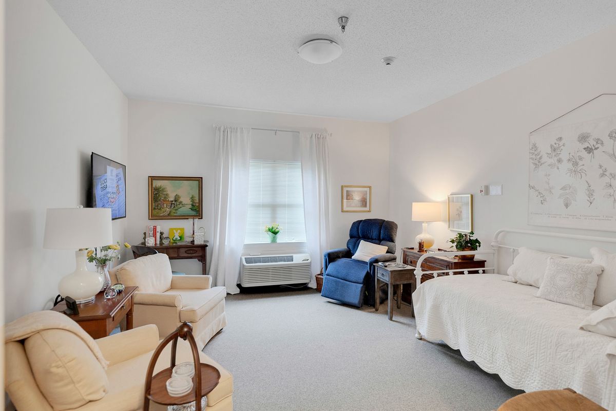 A cozy and well-furnished bedroom with a bed, reclining chair, and various decorative elements.