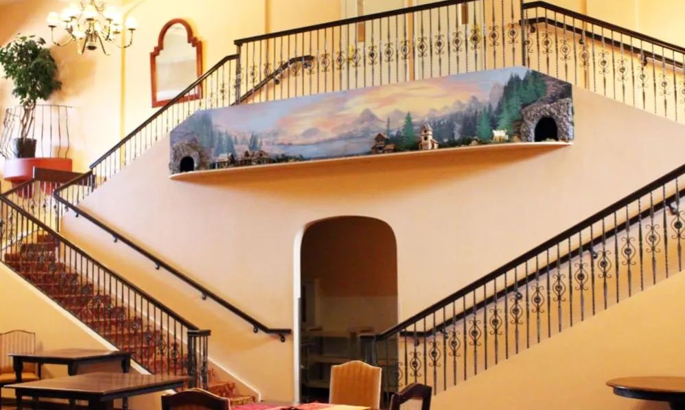 A beautifully decorated interior featuring a split staircase with a scenic mural along the upper wall.