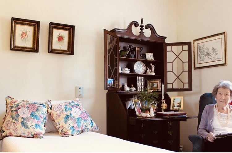 A cozy bedroom corner featuring an antique desk with shelves and floral pillows.