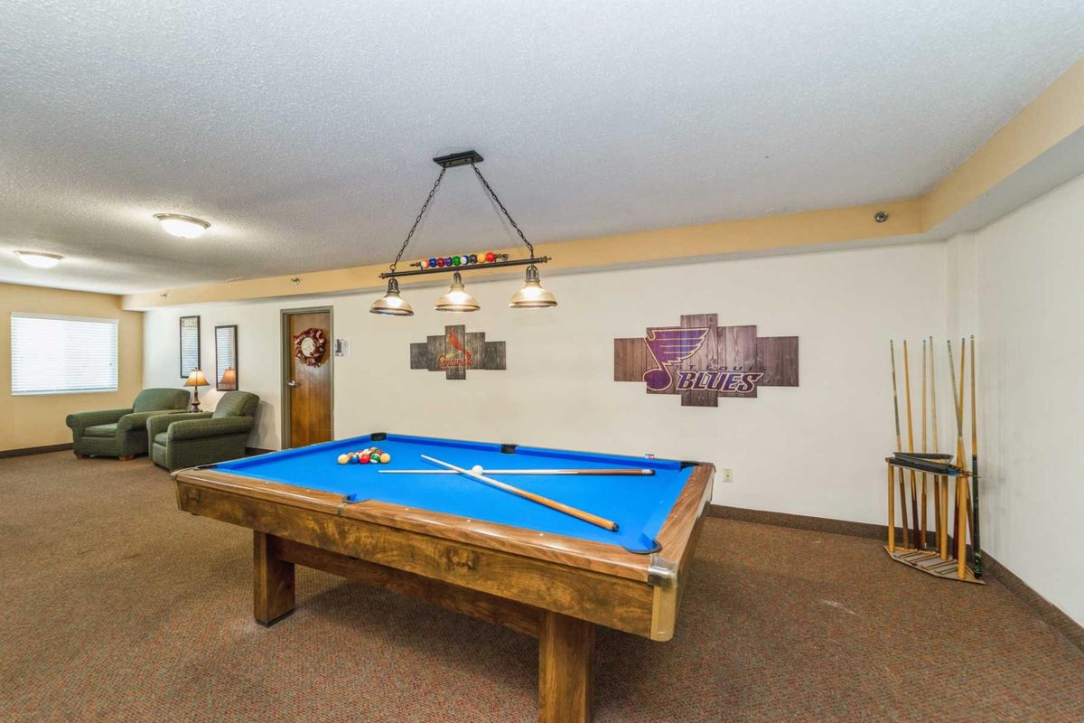 A cozy game room with a blue-felt pool table and stylish lighting.