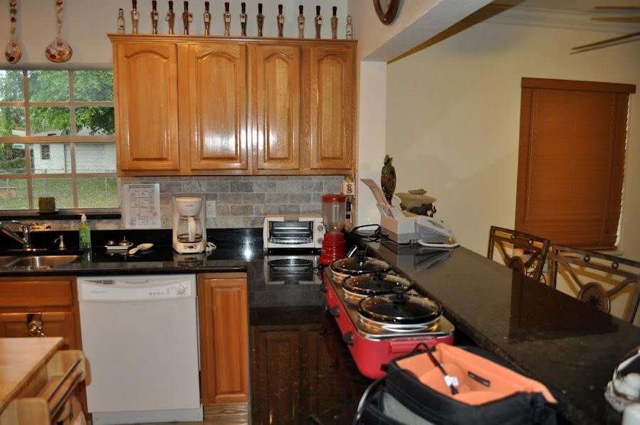 A neatly organized kitchen featuring wooden cabinets, a black countertop, and various appliances including a coffee maker and toaster oven.