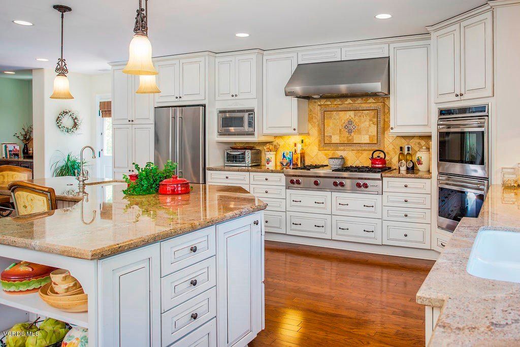 A modern kitchen with white cabinets, stainless steel appliances, and a central island.
