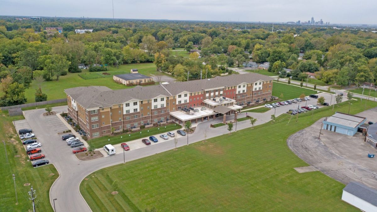 Aerial view of a hotel building surrounded by greenery and parking spaces.