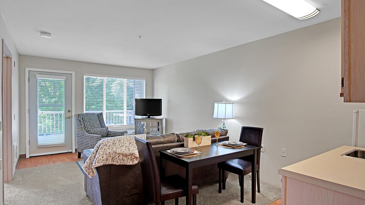 A cozy living and dining area featuring a table, chairs, and a comfortable seating arrangement near a window.