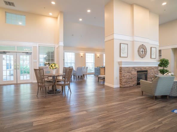 A spacious and well-lit living area featuring a dining table, comfortable seating, a fireplace, and wooden flooring.