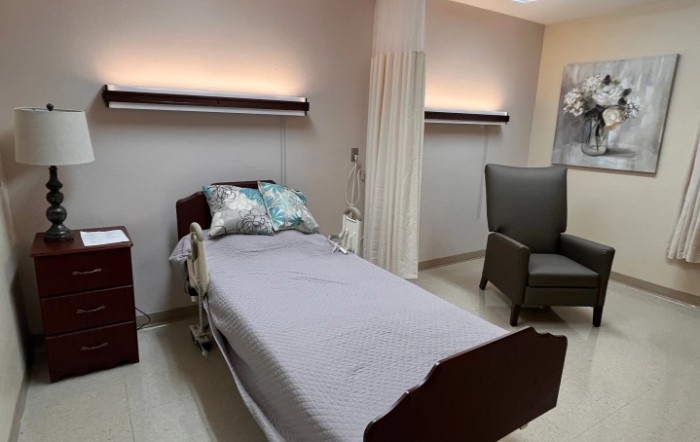 A clean and well-organized hospital room with a patient bed and chair.