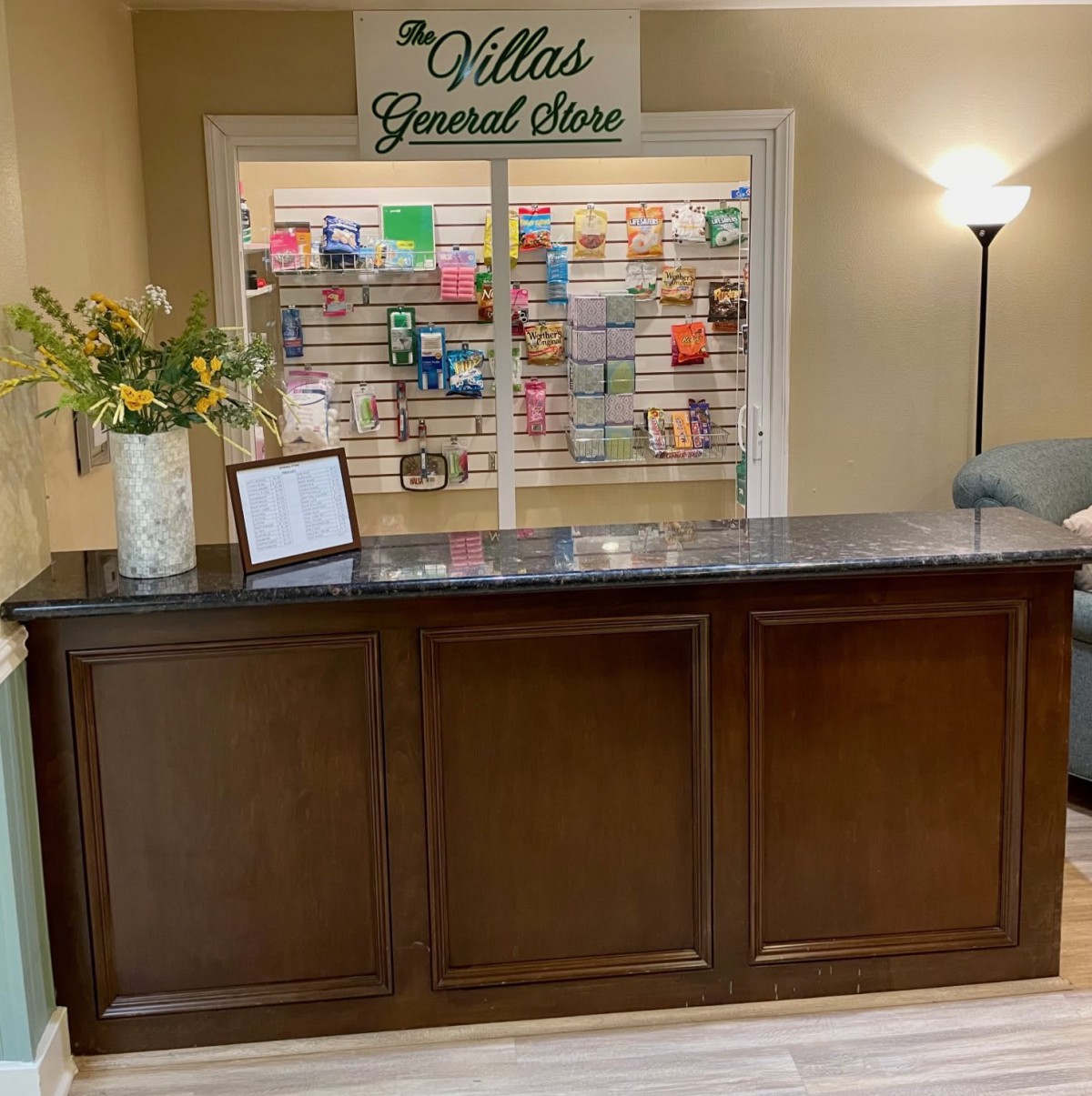 A reception desk with flower arrangements and a display rack in the background.
