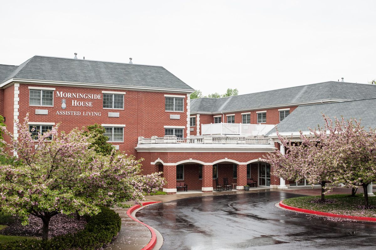 A brick hotel building with an entrance and a parking area in front.