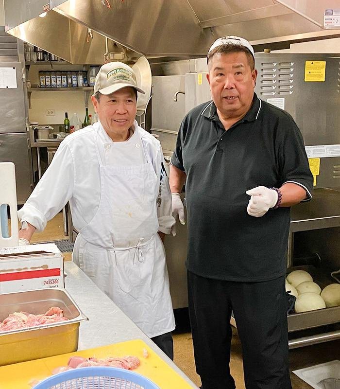 Two chefs in a kitchen preparing food.
