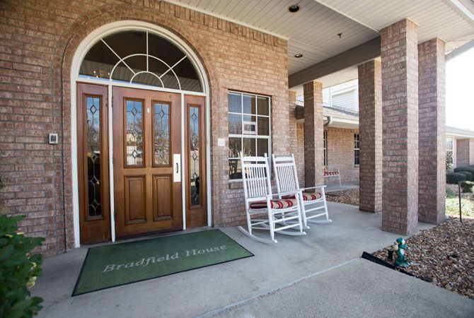 Front entrance of a building with wooden double doors and rocking chairs.