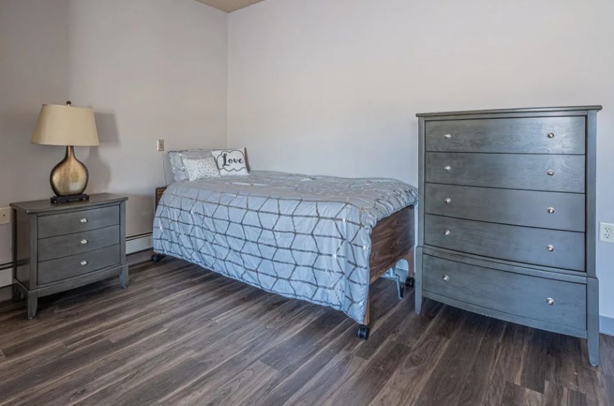 A minimalist bedroom with a single bed, dresser, and nightstand.