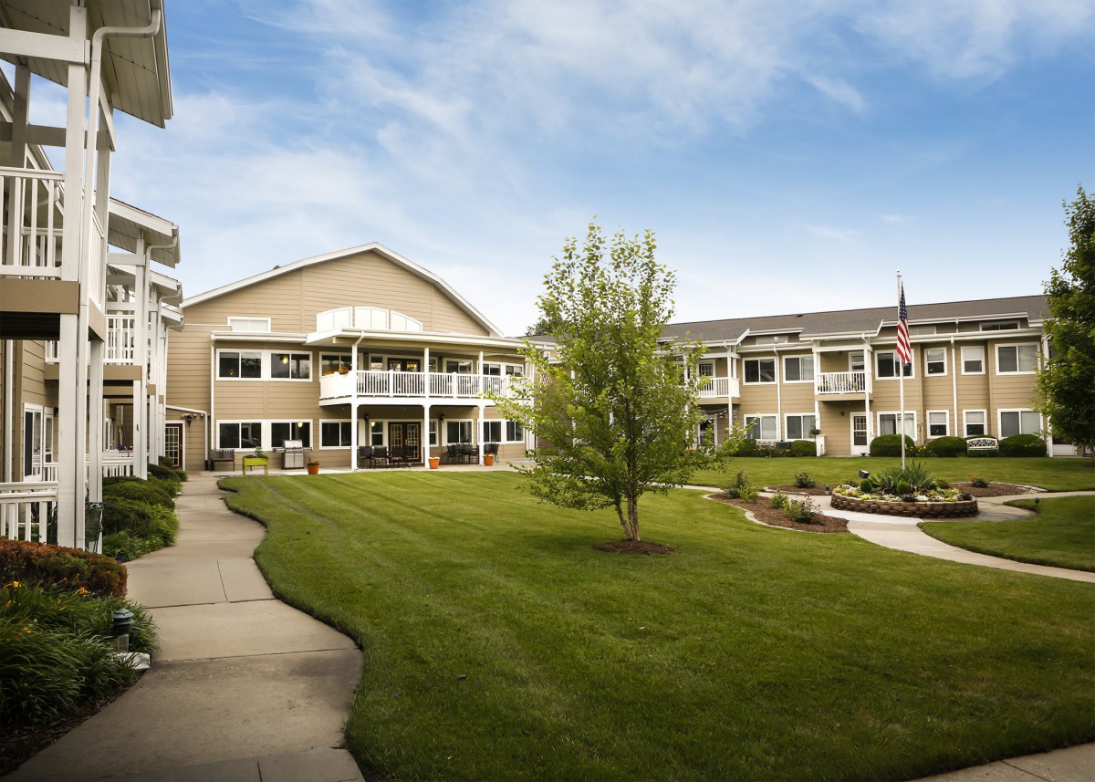 A residential building with a well-maintained lawn and pathways under a partly cloudy sky.