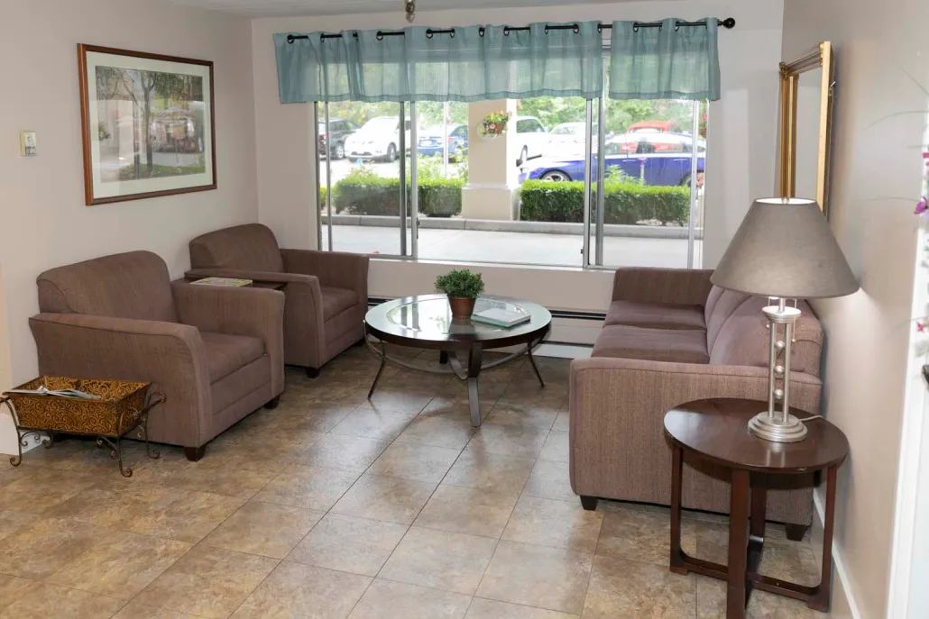 A cozy living room with comfortable sofas and a central glass table, illuminated by natural light from large windows.