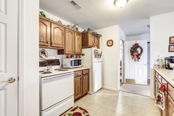 A cozy kitchen with wooden cabinets, featuring a stove, microwave, and refrigerator.